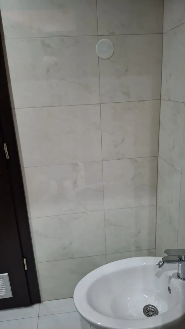 Part of a bathroom with light tiles and a sink.