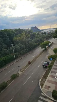 Pogled sa terase na ulicu, zelenilo i more u daljini. - image 9