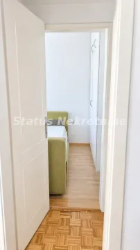 Pogled iz hodnika kroz otvorena vrata na nameštenu spavaću sobu sa krevetom i ormarom. - image 6