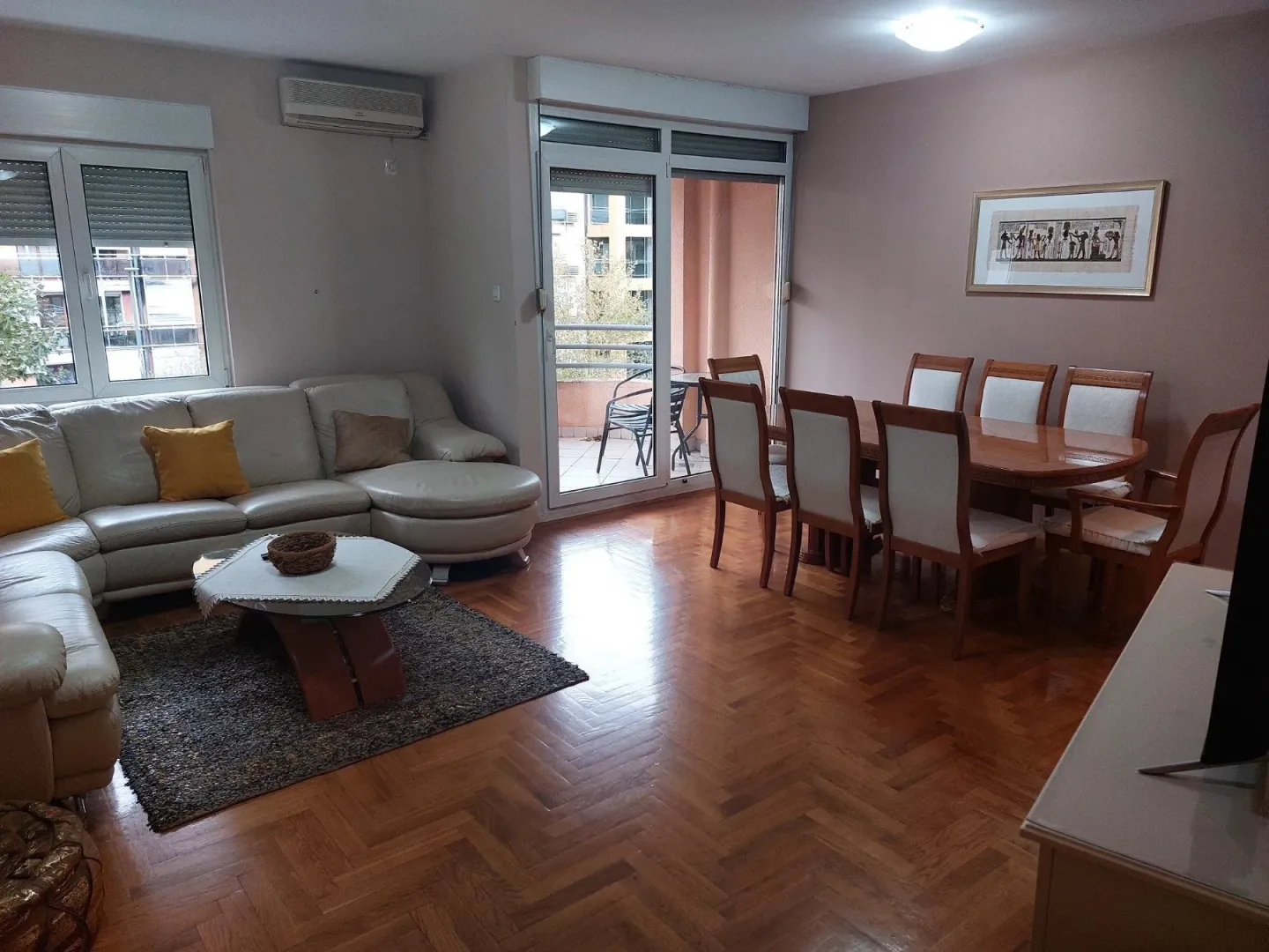 Bright living room featuring a leather sofa set, dining table, and balcony access.