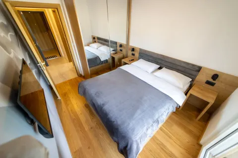 Moderna spavaća soba sa bračnim krevetom, drvenim podom i ugradnim plakarom sa ogledalom. - image 12