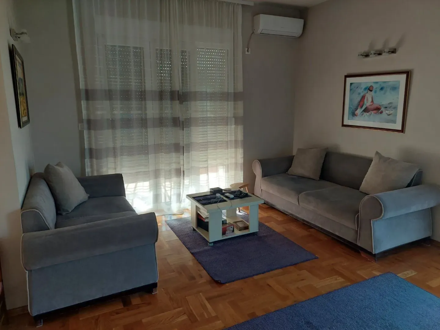 Living room with two grey sofas and wooden flooring.