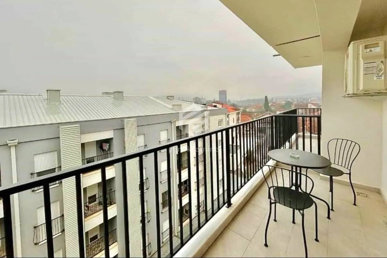 Covered balcony with patio furniture and a view of surrounding buildings.