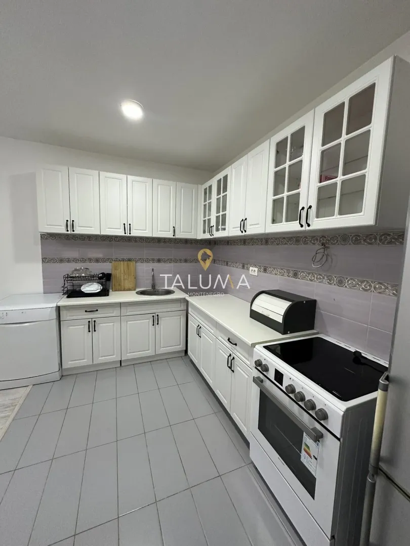 Kitchen with white cabinetry, sink, and stove.