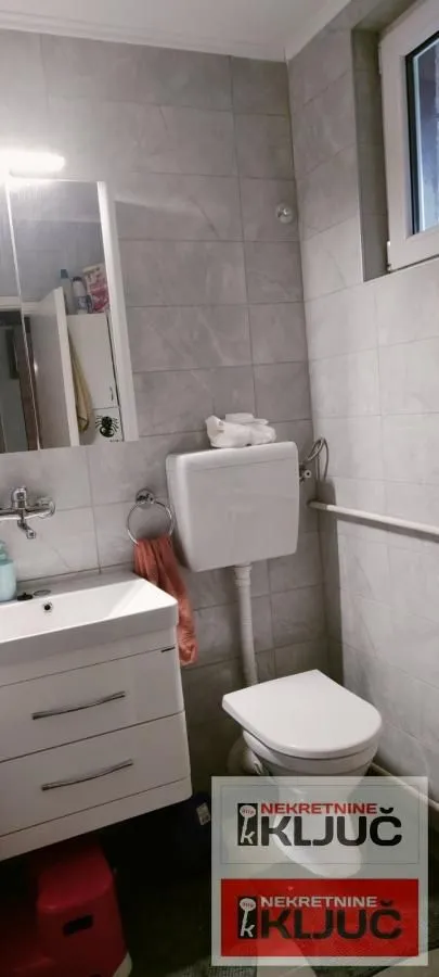 Manje kupatilo sa umivaonikom, WC šoljom i ogledalom sa ormarićem.