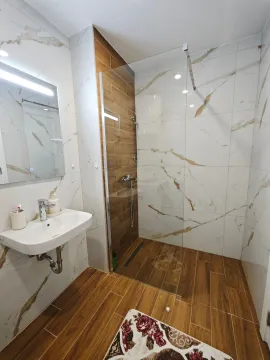 Modern bathroom with a walk-in shower, washbasin, and mirror. - image 7