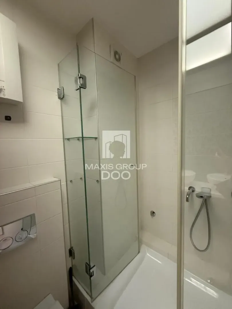 Bathroom with a shower cabin and a wall-mounted toilet.