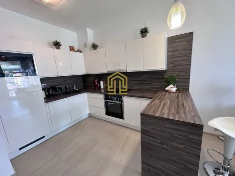 Modern kitchen with white cabinets, dark countertops and a breakfast bar. - image 5