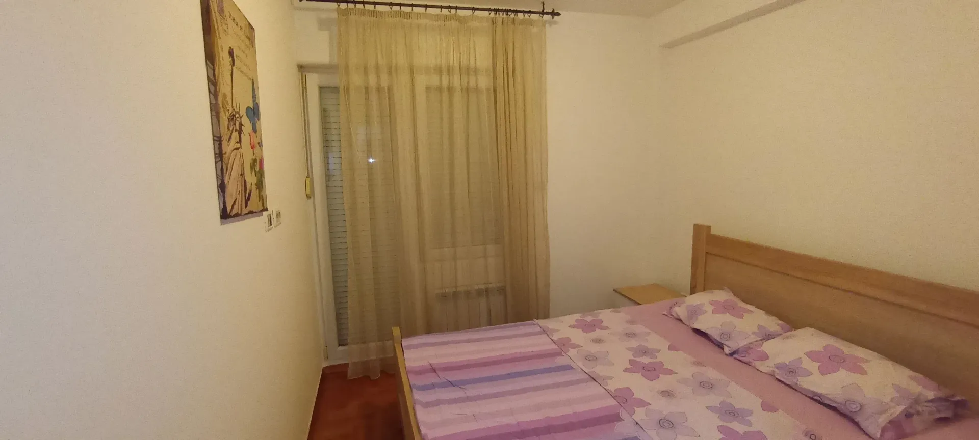 A simple bedroom with a double bed and balcony access.