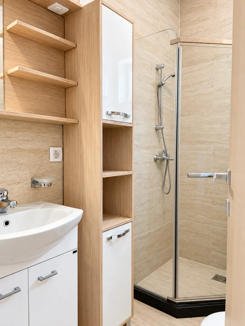 Modernly equipped bathroom with a shower cabin and wooden elements.