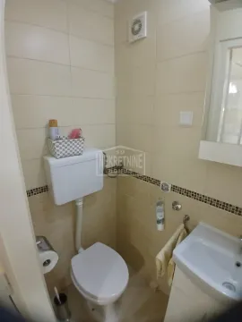 Manje kupatilo sa WC šoljom, umivaonikom i bež pločicama. - image 11