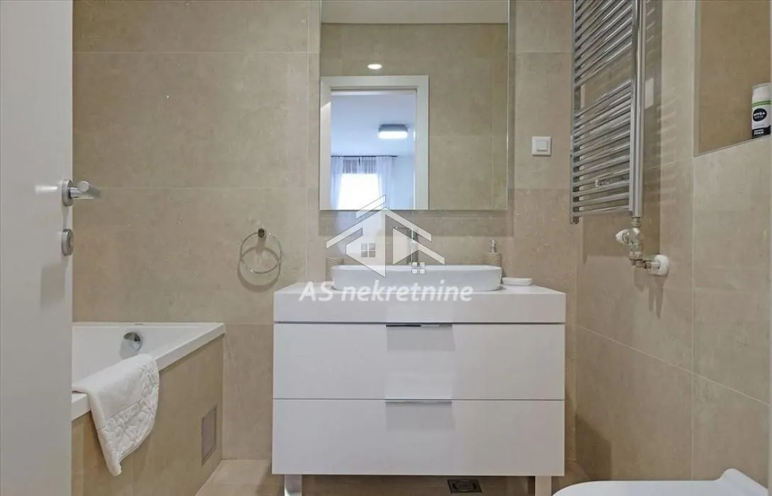 Modern bathroom with a washbasin, mirror and bathtub.