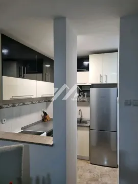 A view of a modern equipped kitchen with white and dark cabinetry and a refrigerator. - image 8