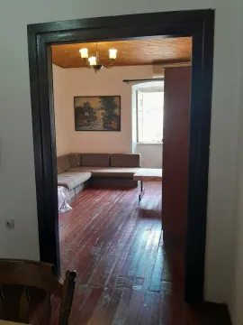 Pogled kroz vrata na dnevnu sobu sa garniturom i drvenim podom. - image 8