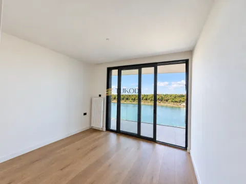 Empty room with wooden flooring and large sliding doors leading to a terrace with a river view. - image 9
