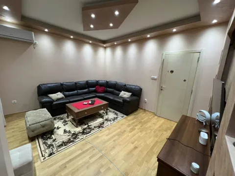 Living room with a black sectional sofa, wooden coffee table, and parquet flooring. - image 11