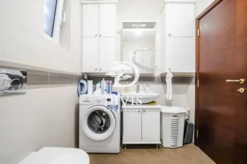 Bathroom equipped with a sink, cabinets, toilet, and washing machine. - image 9