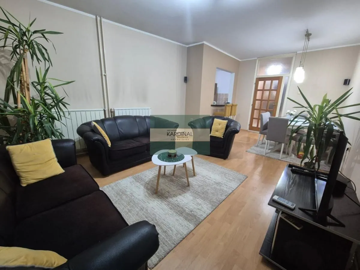 Dnevni boravak sa garniturom i trpezarijom u pozadini.
