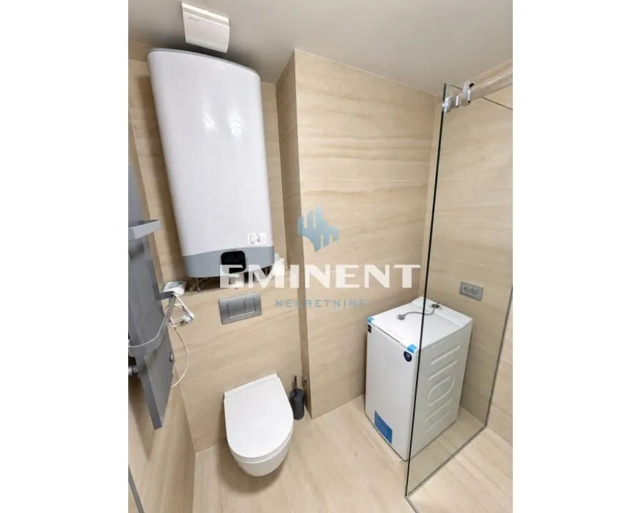 View of a modern bathroom equipped with a shower cabin, toilet, and water heater.
