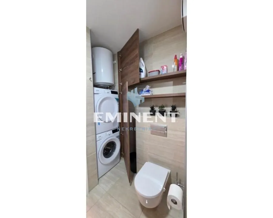 Bathroom equipped with a toilet, shower, and built-in washer and dryer.