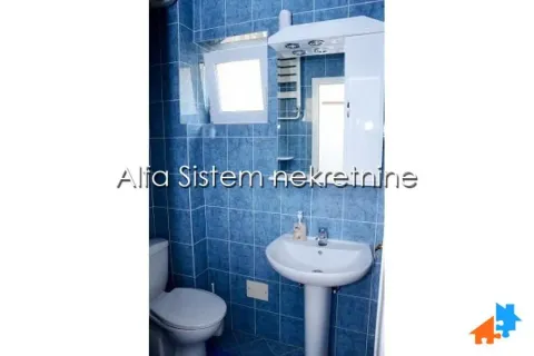 Bathroom tiled in blue with a washbasin, mirror, and toilet bowl. - image 3