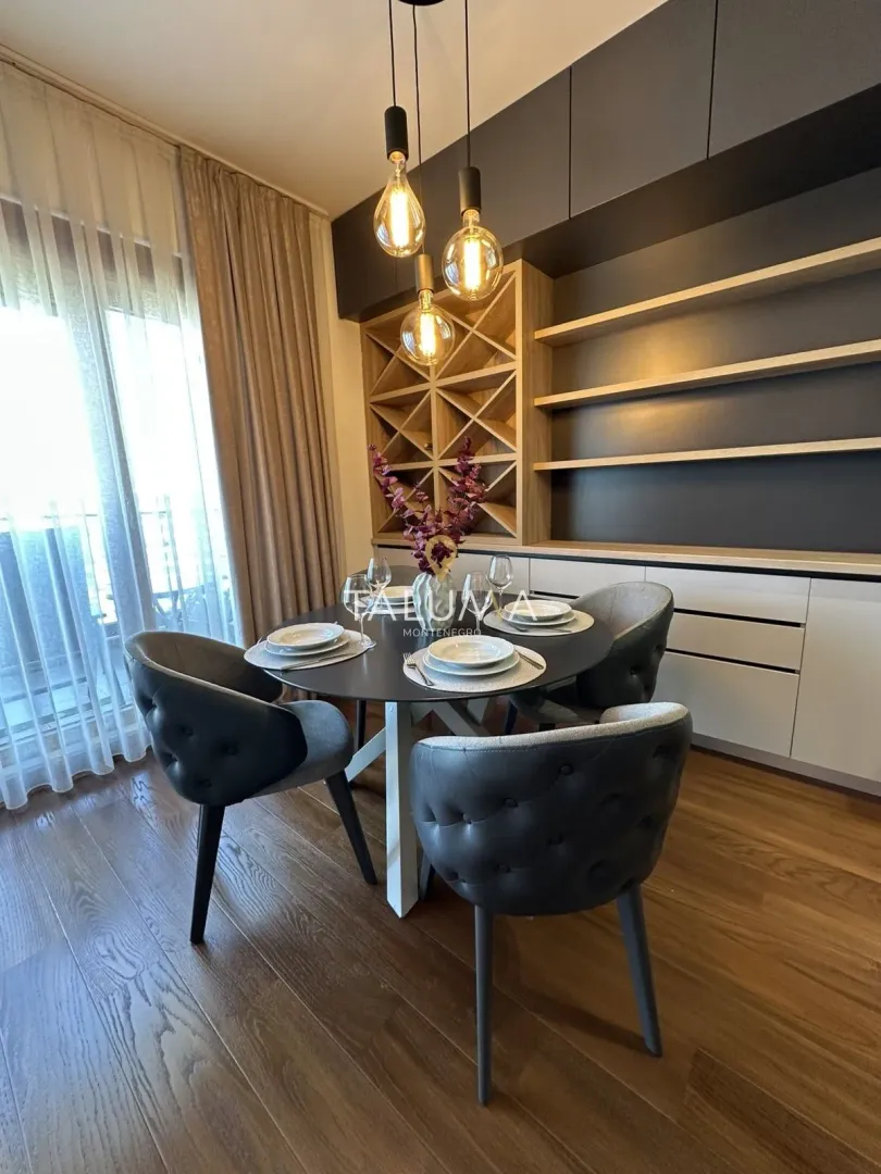 Trpezarija sa okruglim stolom, modernim stolicama i ugradnim elementima na zidu.