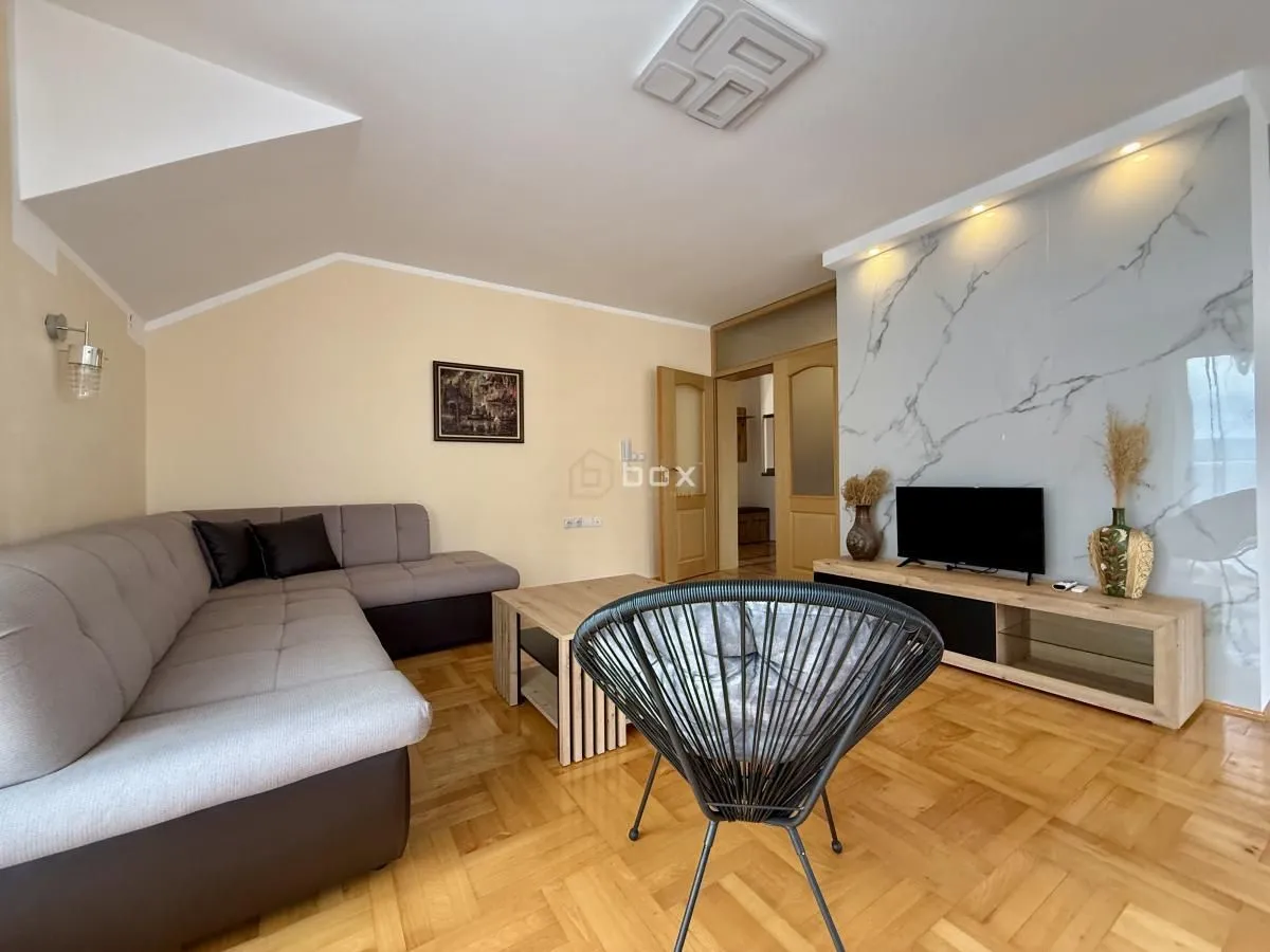 Living room with a sofa, TV, and parquet flooring.
