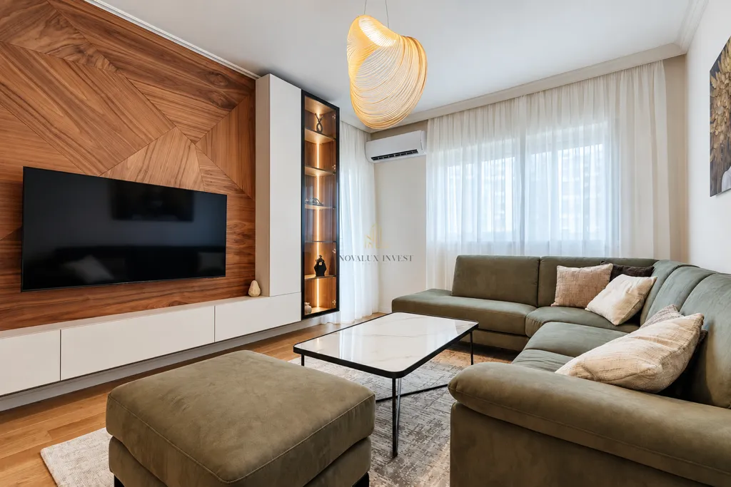 Modern living room with a sectional sofa, TV and decorative wooden wall.