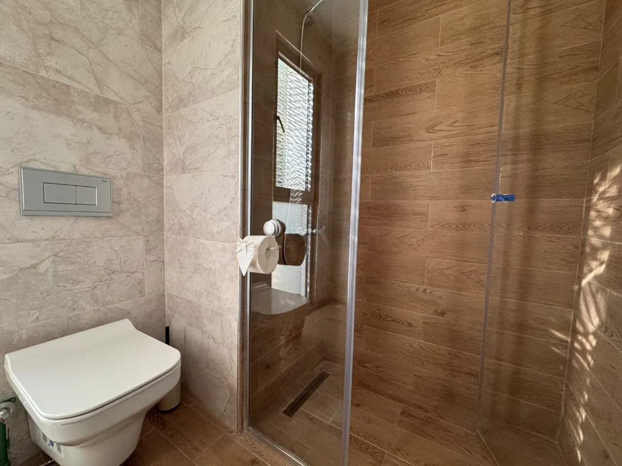 Moderne kupatilo sa tuš kabinom i ugradnom wc šoljom.