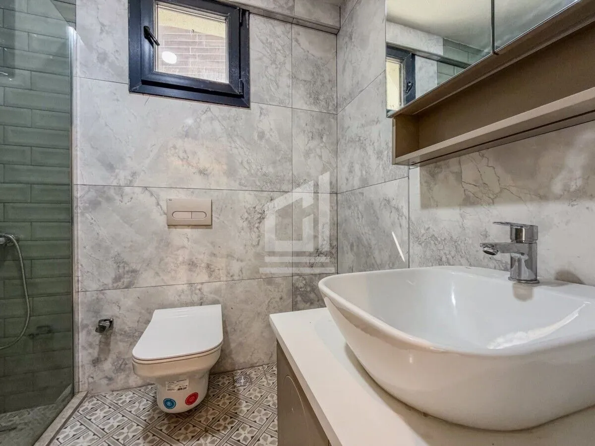 Moderno opremljeno kupatilo sa umivaonikom, WC šoljom i tuš kabinom.