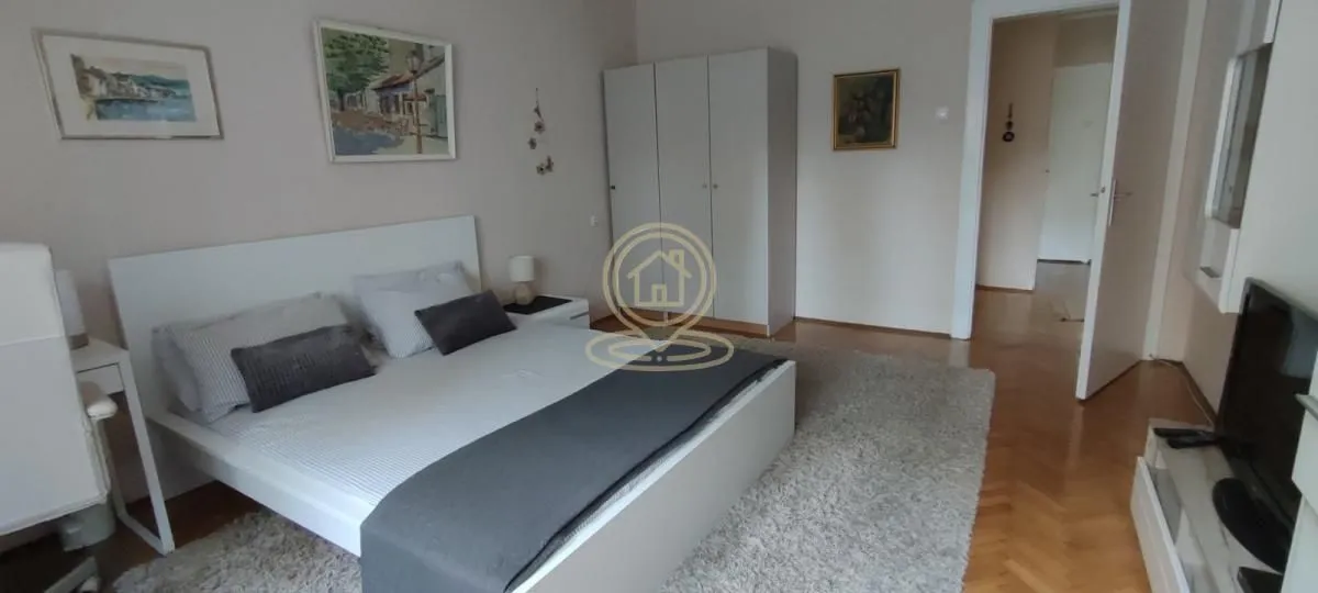 Prostrana spavaća soba sa bračnim krevetom, garderoberom i parketom.