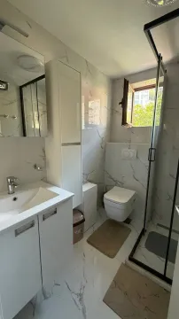 Moderno opremljeno kupatilo sa bijelim pločicama i tuš kabinom. - image 6
