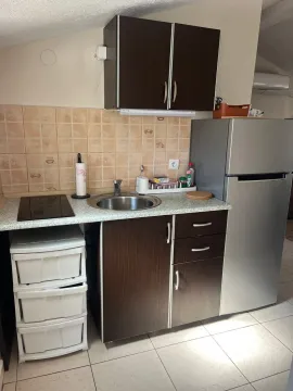 Small kitchen with dark wood-toned cabinets and a refrigerator. - image 4