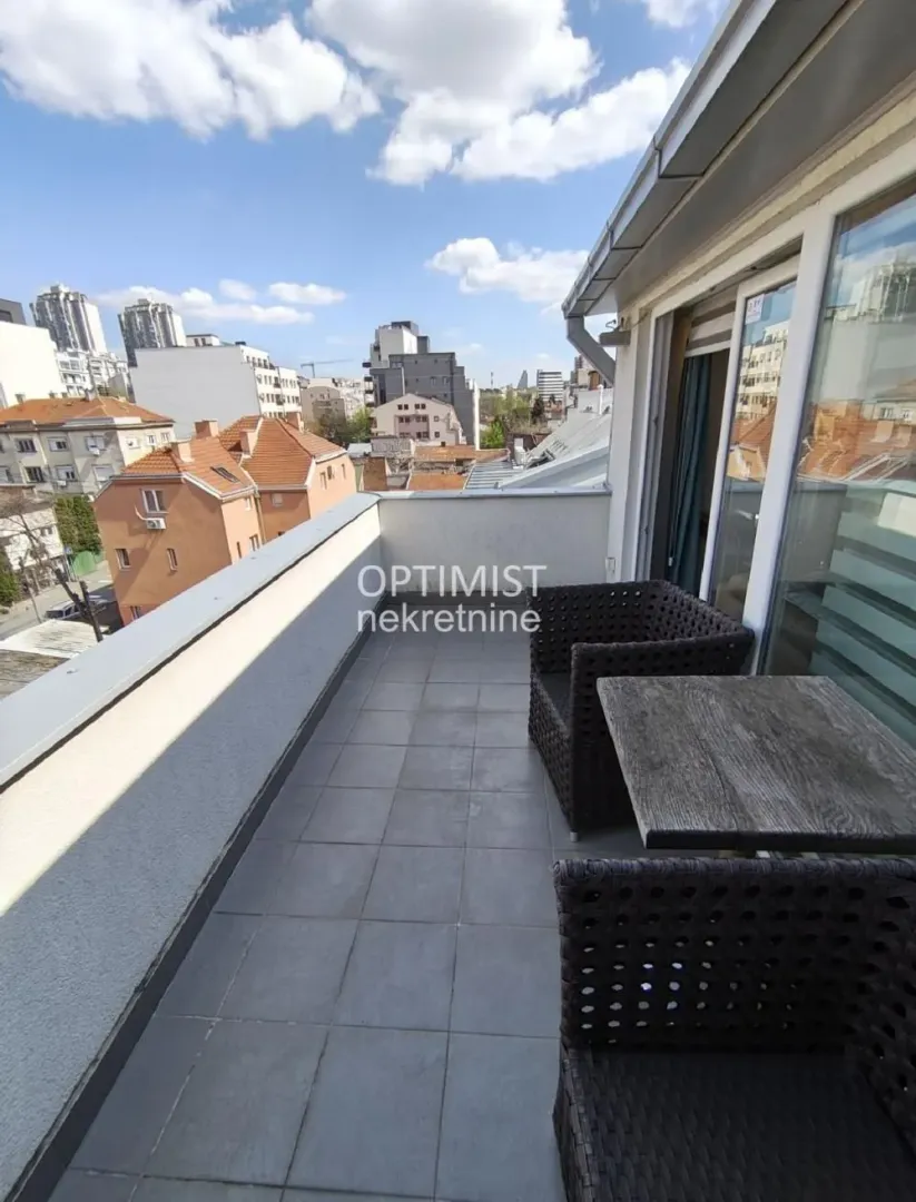Namešten balkon sa garniturom za sedenje i pogledom na grad.