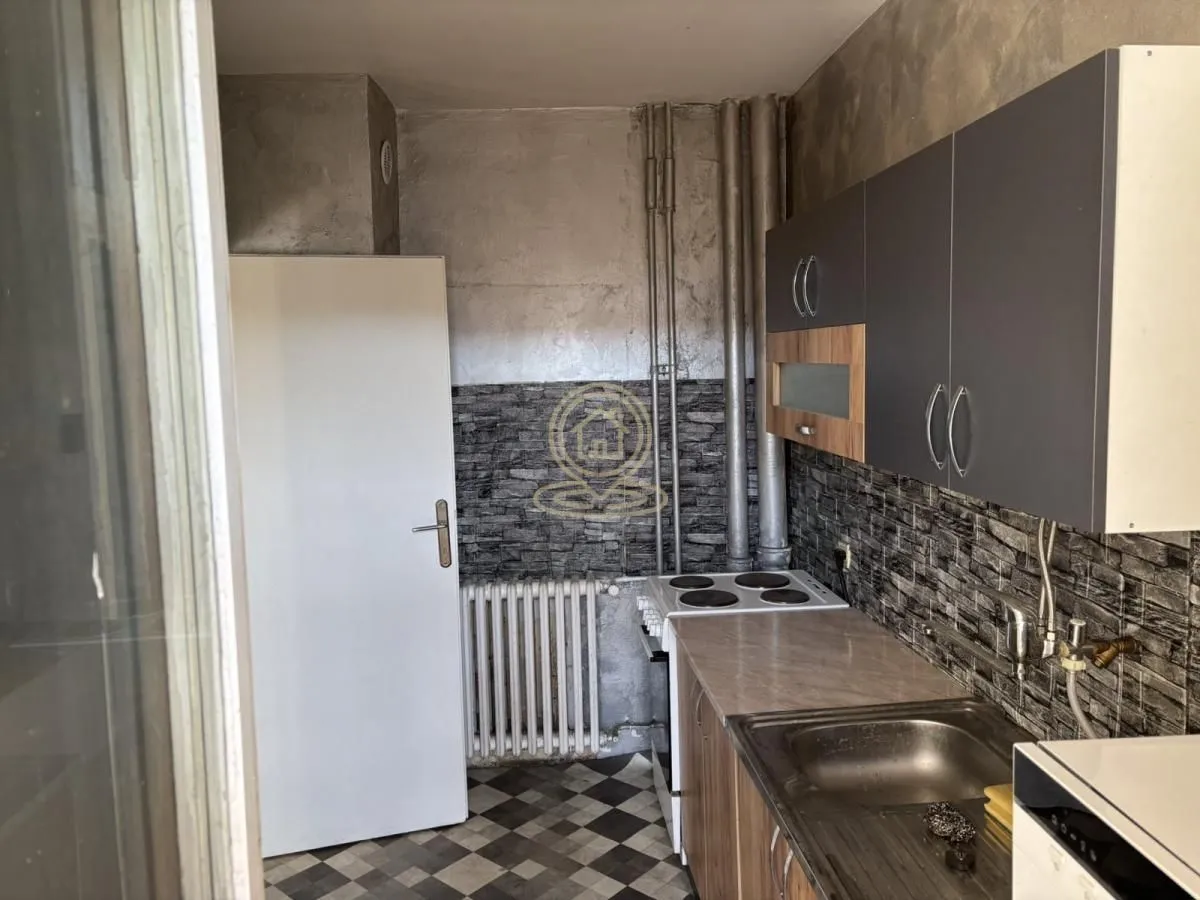 Small kitchen with a sink, stove, and upper cabinets.
