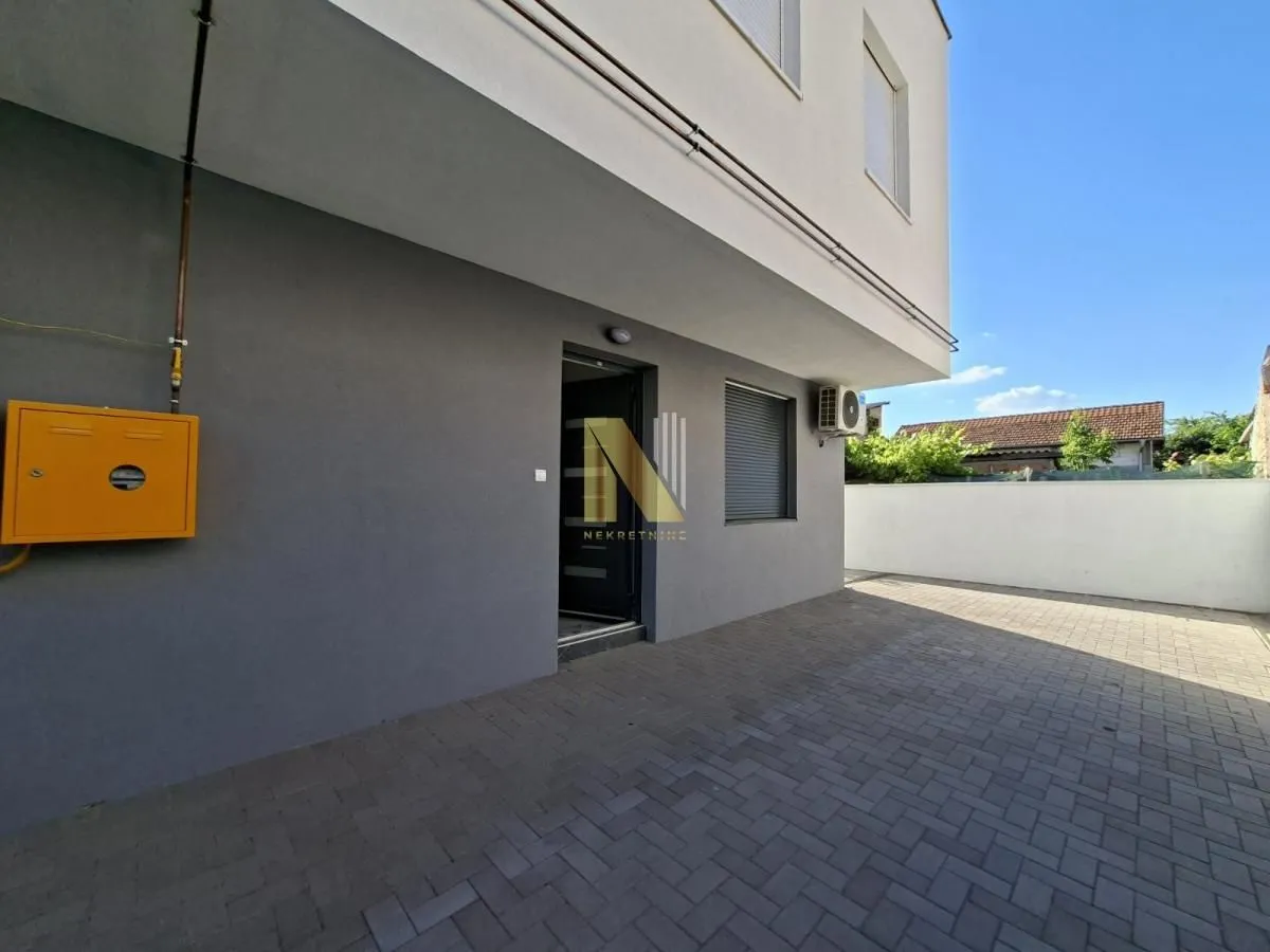View of the courtyard and building entrance with a paved patio.