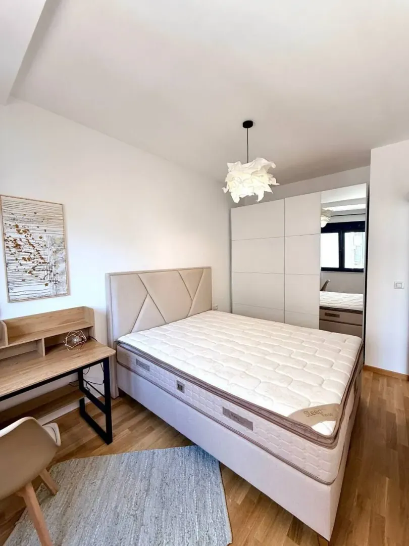 Furnished bedroom with a double bed, wardrobe, and a desk.