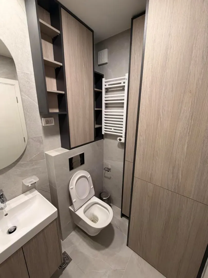Moderno opremljeno kupatilo sa ugradnim ormarićima, WC šoljom i umivaonikom.