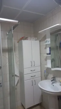 Jednostavno kupatilo sa bijelim ormarićem, umivaonikom i tuš kabinom. - image 14