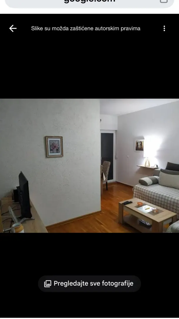 Dnevna soba sa garniturom, stočićem i televizorom.