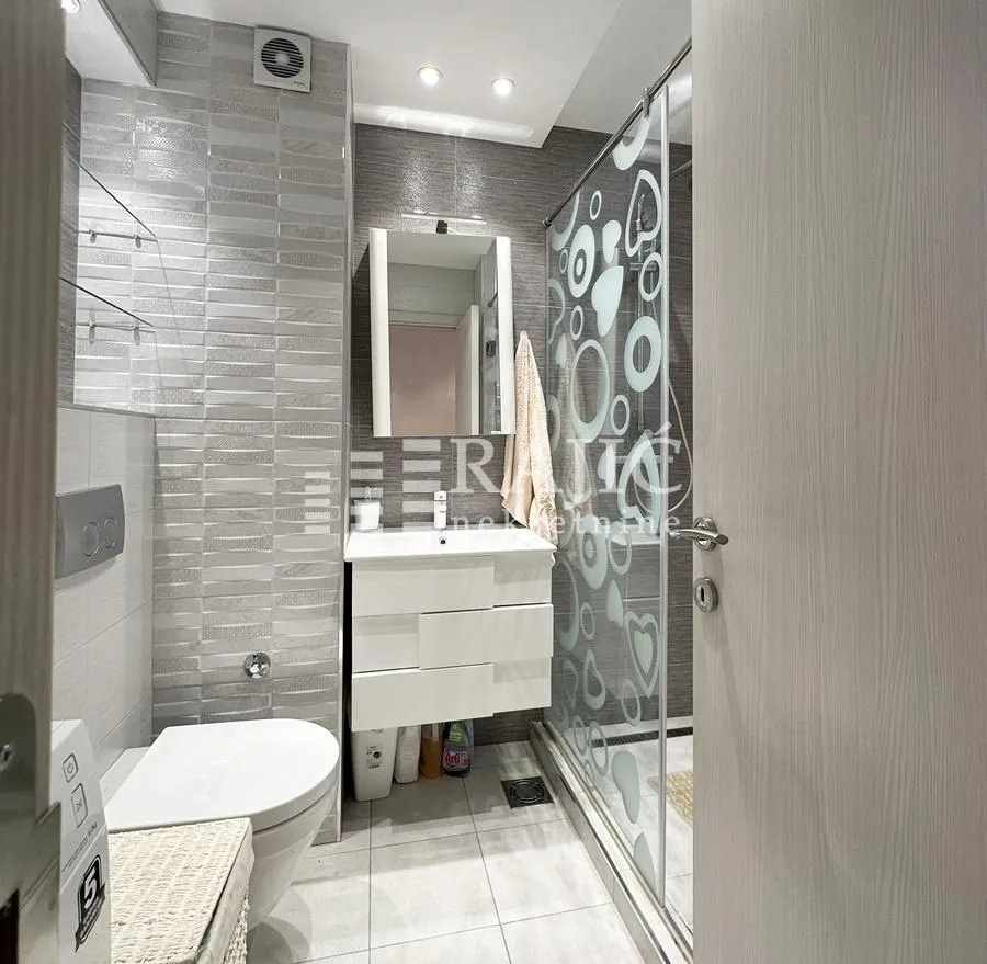 Modern bathroom with a washbasin, toilet, and walk-in shower.