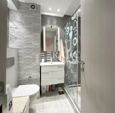 Modern bathroom with a washbasin, toilet, and walk-in shower. - image 11