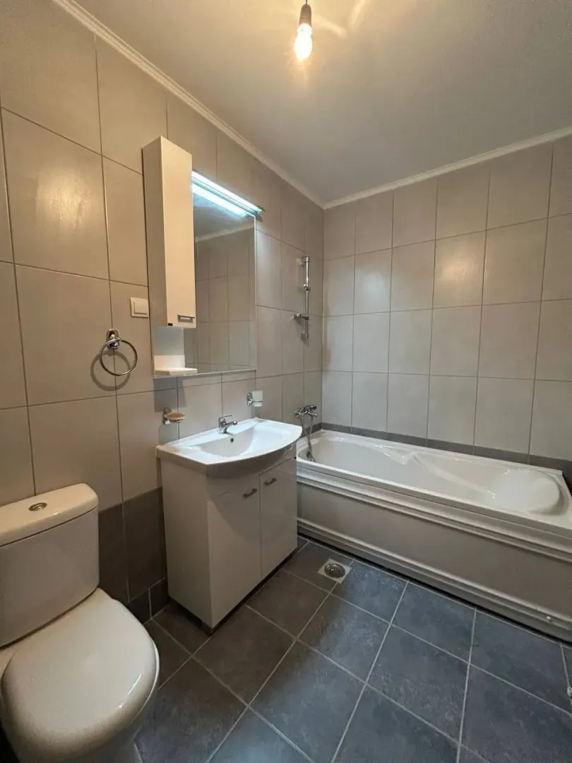 Kupatilo opremljeno kadom, umivaonikom sa ormarićem i WC šoljom.