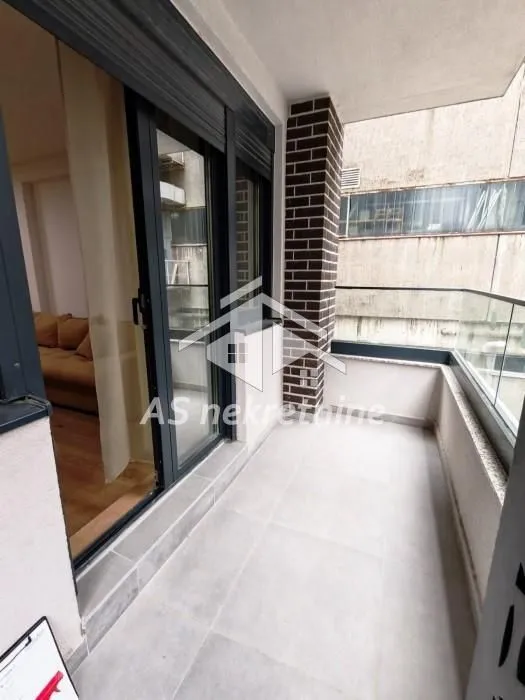 Furnished balcony with a glass railing and exterior view.