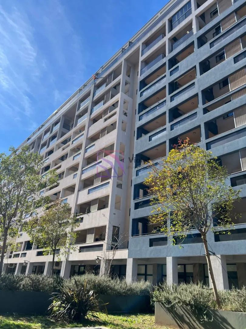 View of a modern residential building with balconies and a landscaped yard.
