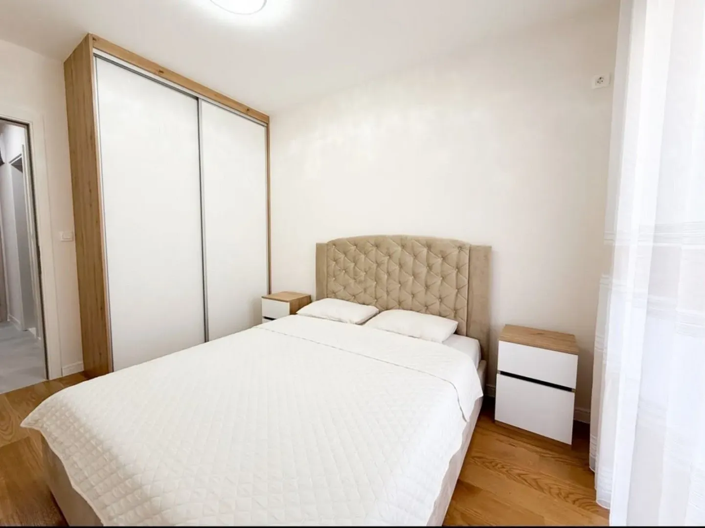 Bright bedroom with a double bed, wardrobe, and nightstands.