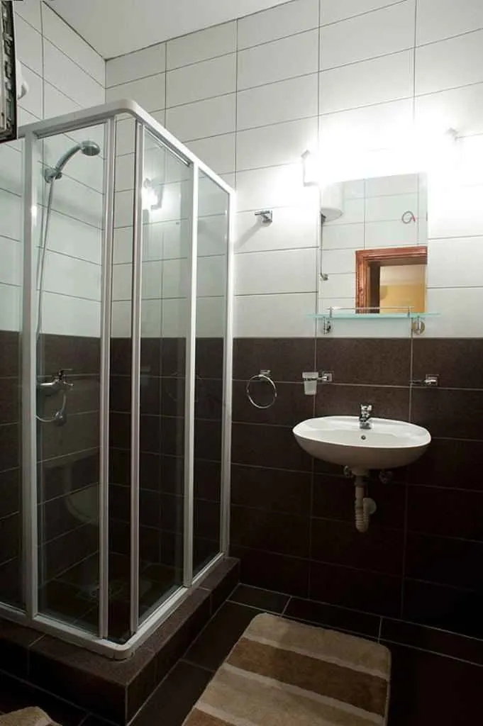 Kupatilo sa tuš kabinom, umivaonikom i ogledalom.