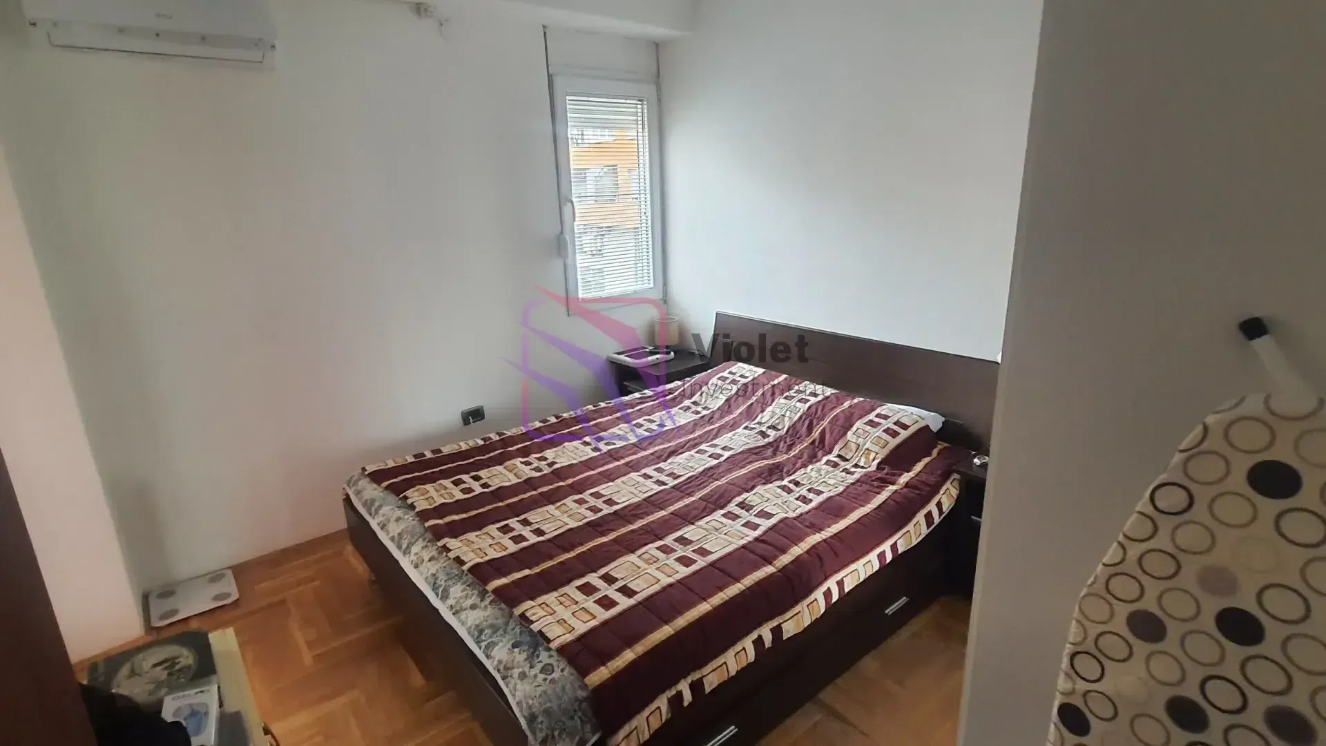 Small bedroom with a double bed, parquet flooring, and a window.