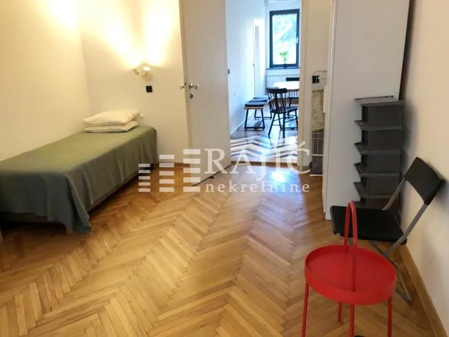 Smaller bedroom with a bed and parquet flooring.