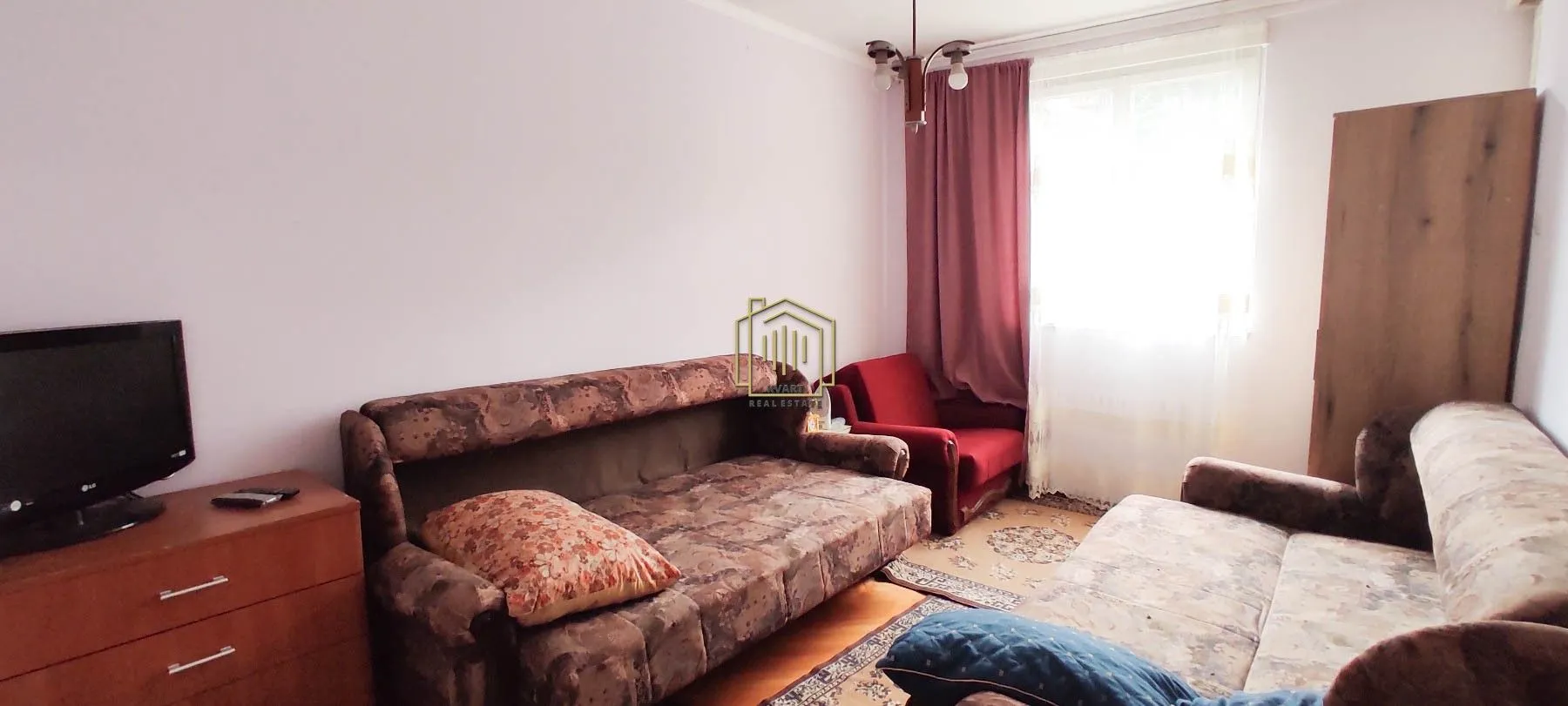 Living room with seating furniture, a TV, and a window.